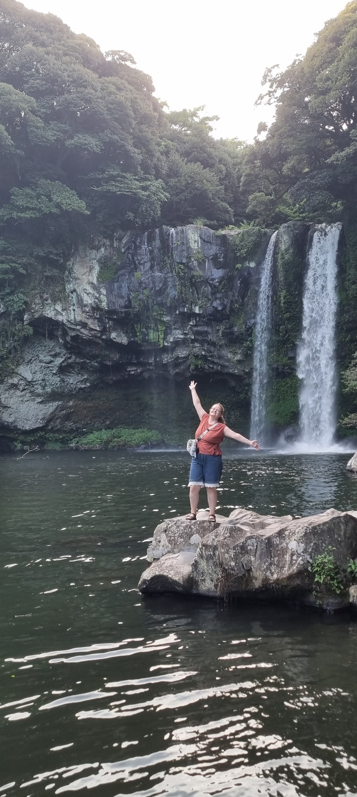 Abilene standing in front of a waterfall surrounded by trees